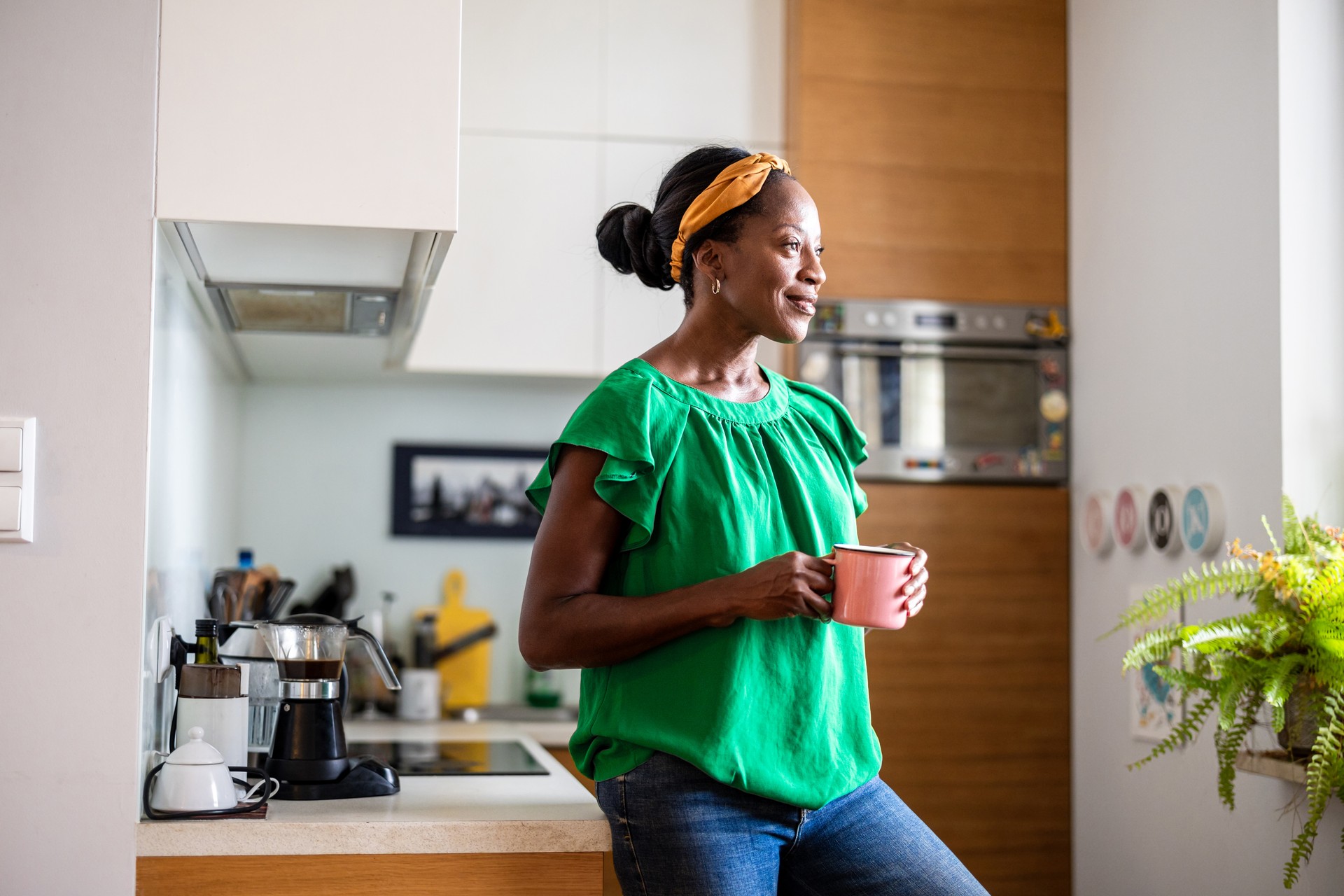 Retrato de uma mulher sorridente e madura em pé em sua cozinha